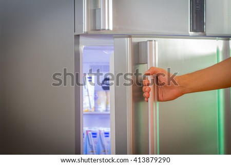 Hand a woman is opening a refrigerator door