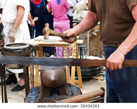 man making an iron blade with anvil and hammer