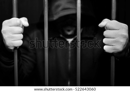 Abstract. Hands of the prisoner on a steel lattice close up. Prison, man in handcuffs.