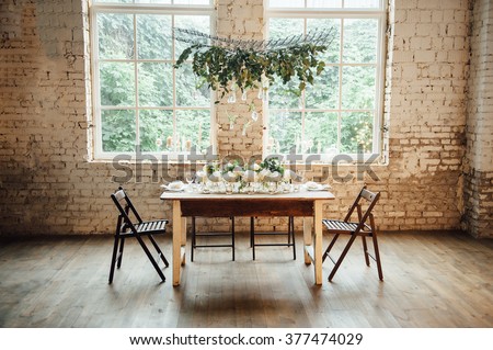 Wedding room decorated loft style with a table and other accessories candles , peonies , bulbs , bricks , window