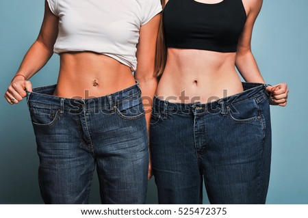 Women shows her weight loss. Isolated on blue background