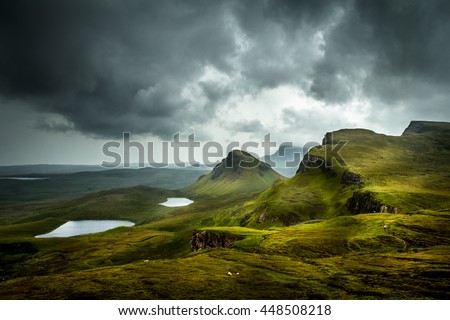 Scenic view of beautiful landscape the Quiraing, Isle of Skye, Scotland from above with view into the valley and hills in the background and dramatic clouds in the sky