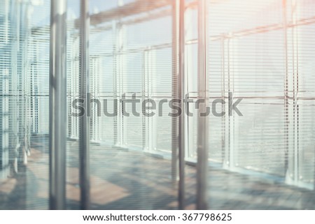 Abstract office interior background, the sun rays with flares, glass, steel columns and blinds, view from skyscraper through the window, the cityscape outside