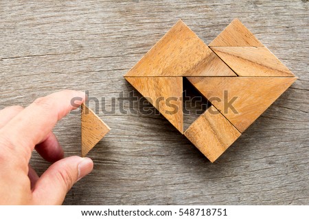 Man held piece of tangram puzzle to fulfill the heart shape on wooden table (Concept of love)