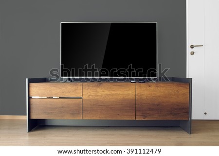 Led TV on TV stand in empty room with black wall. decorate in loft style.