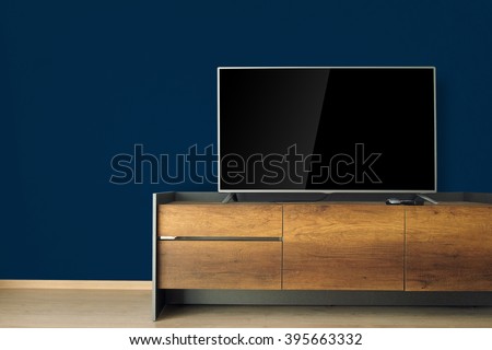 Led TV on TV stand with dark blue wall. led, tv, television, wooden furniture, wood texture, empty room, living room, home decor, blank screen, laminate floor