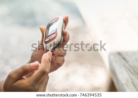 Close up of woman hands checking blood sugar level by Glucose meter using as Medicine, diabetes, glycemia, health care and people concept.
