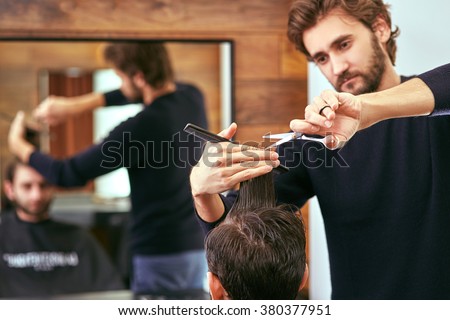 barber cutting hair with scissors. back view of man in barber shop.
