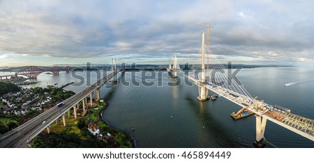 The new Queensferry Crossing bridge (on the right) under construction over the Firth of Forth with the older Forth Road bridge (on the left) and with the iconic Forth Rail Bridge in the far left.
