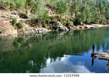 calm and peaceful waters of a lake with silhouette of a person contemplating nature