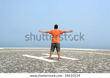 boy with arms wide open contemplating the ocean in foggy day