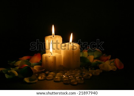 three candles and petals with warm and magic light in black background