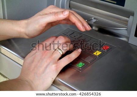 woman\'s hand covers his hand when entering your PIN into an ATM