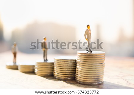 Miniature people: Small figure standing on stack of coin. Money and financial concepts.
