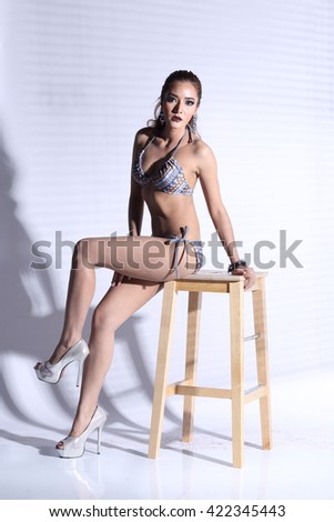 Asian Thai Female Woman Model Tan Skin in Grey Dot Bikini Sport Swim wear Suit Wet Hair, Studio Lighting Shadow on White Background, Sexy Pose sit on wooden stool Full body, contrast shadow concept