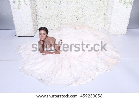 Lovely Asia Model in Wedding Dress sit on the ground with wide circle of skirt , studio lighting