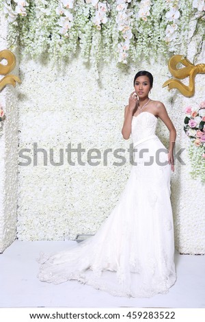 Copy Space for text, Concept of Wedding Bridal Dress in Tan Skin Asia Girl in front of Flower Wall decorative, studio lighting full body