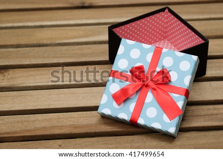 light blue and white polka dot with red ribbon  gift box  on wood table with green background