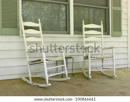 Two old white painted wooden rocking chairs on a front porch