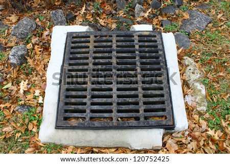 An old rusted and cracked cast iron storm drain for storm water runoff in the ground.
