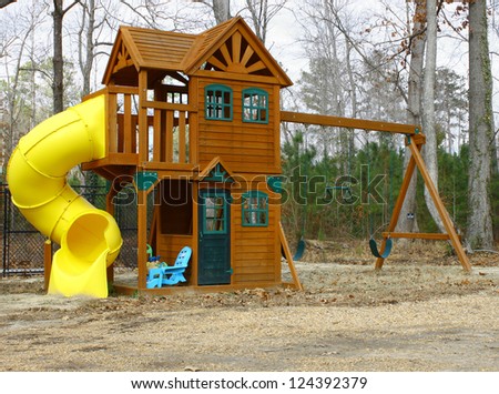 A child\'s play-set swing and slide outside on a cloudy winter day