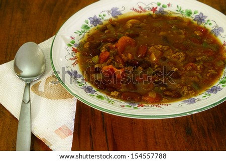 A fresh made bowl of Chili beans also known as chili con carne in a ceramic bowl on a wooden table