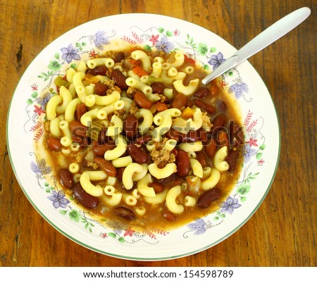 A fresh bowl of Chili beans and noodles in a ceramic bowl on a wooden table