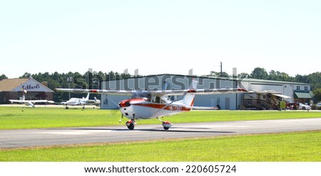 MIDDLESEX, VA - SEPTEMBER 27, 2014: A red & white personal airplane headed down the runway for takeoff in the wings wheels and keels annual show at the Hummel airfield airstrip in Middlesex VA