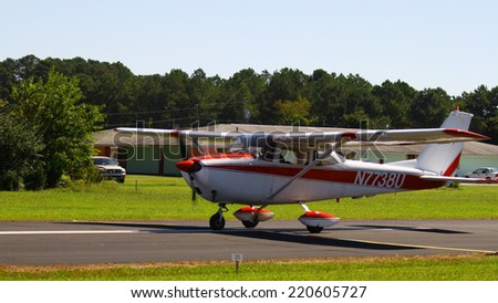 MIDDLESEX, VA - SEPTEMBER 27, 2014: A red & white personal airplane headed down the runway for takeoff in the wings wheels and keels annual show at the Hummel airfield airstrip in Middlesex VA