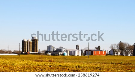 A farmers agricultural silos and equipment among the field where he works outside during the winter