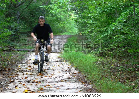 A Man on a Mountain bicycle with a LED flashlight for a headlight riding through the woods with room for your text.