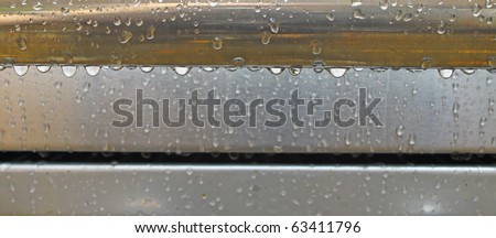 Fresh rain drops hanging and dripping off of a handle from a grill with room for your text