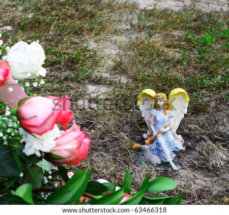 A Beautiful Angel figurine in the background on the ground amongst some flowers using selective focus with room for your text.