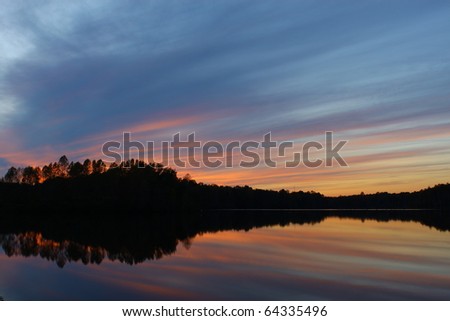 A Beautiful silhouetted shoreline of a fall Sunset over a peaceful and serene reservoir with room for your text
