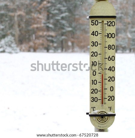 An old dirty red mercury thermometer covered with snow strapped on a post outside using a shallow depth of field and selective focus with room for your text.