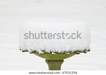 A fresh frosty snow covered birdbath outside in the snow after a Blizzard rolled through with room for your text