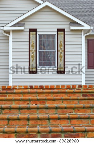 A window in a vinyl sided house with a curtain in it along with etched glass side windows on both sides and a staircase leading up to a porch with room for your text.