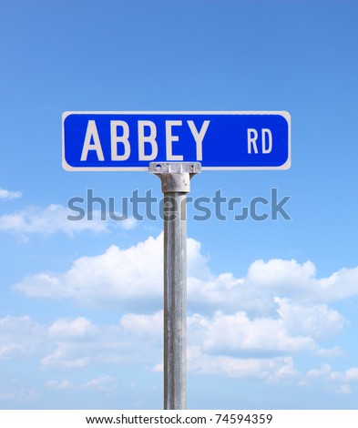 An Abbey road sign against a bright blue cloud filled sky using selective focus and a shallow depth of field with room for your text.