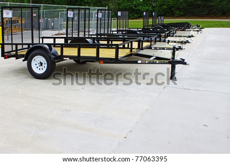 A row of brand new utility trailers lined up and locked together outside for sale with room for your text.