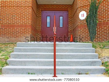 Concrete stairs and a railing leading up and to two metal doors in a brick building with room for your text.