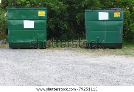 Two trash and waste dumpsters outside of a parking lot for refuse disposal with room for your text.