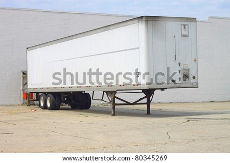 A Big Rigs fifty three foot trailer backed up to the rear door of a building and dropped off waiting to be hauled to it\'s next destination.