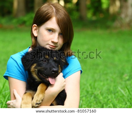 A young girl and her new puppy Bear outside in the  grass using a shallow depth of field with room for your text.