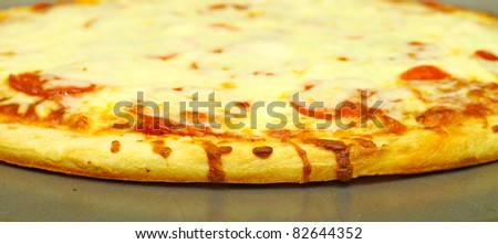A fresh baked extra Pepperoni and extra Cheese Pizza Pie on the pie pan using a shallow depth of field and selective focus