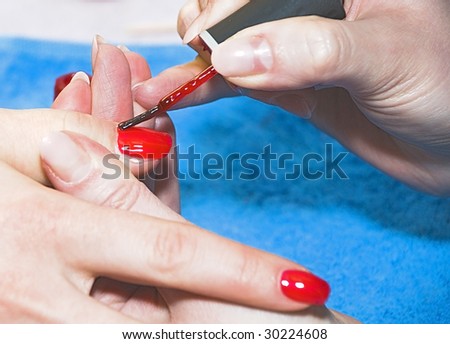 Painting of nails on female fingers a red varnish by means of brush