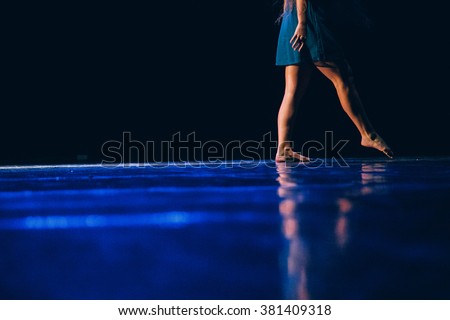 The feet of a young contemporary dancer on blue floor