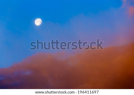 Full moon in cloudy blue sky
