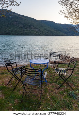 Vintage iron table and chairs in front of Ladonas Lake, Greece in the afternoon