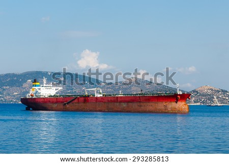 Anchored red, oil tanker near Elefsina port in Greece against a blue sky