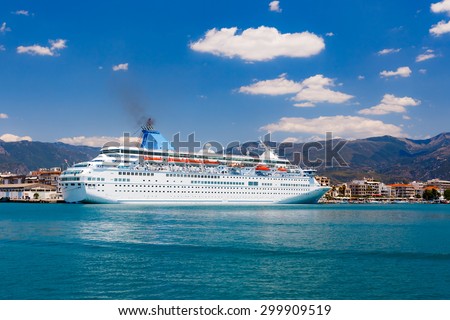 Big cruise ship anchored in port against a blue sky and clouds in Greece